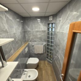 Nebojte se neobvyklých kombinací! Šedý elegantní mramor spolu s dřevodekorem tvoří kompaktní celek - koupelnu, kde se budete cítit dobře.